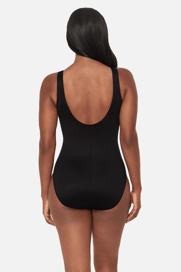 Woman turned away wearing a multicolored geometric high neck one-piece swimsuit