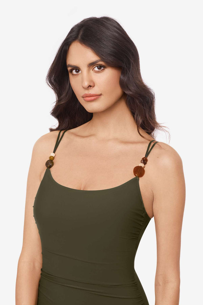 Close up of woman wearing a bamboo green one-piece swimsuit with beads on the straps