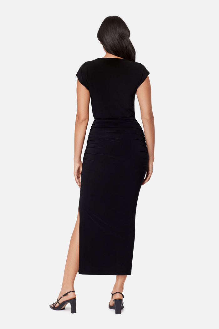 Woman turned away wearing a black short sleeve dress with side slit
