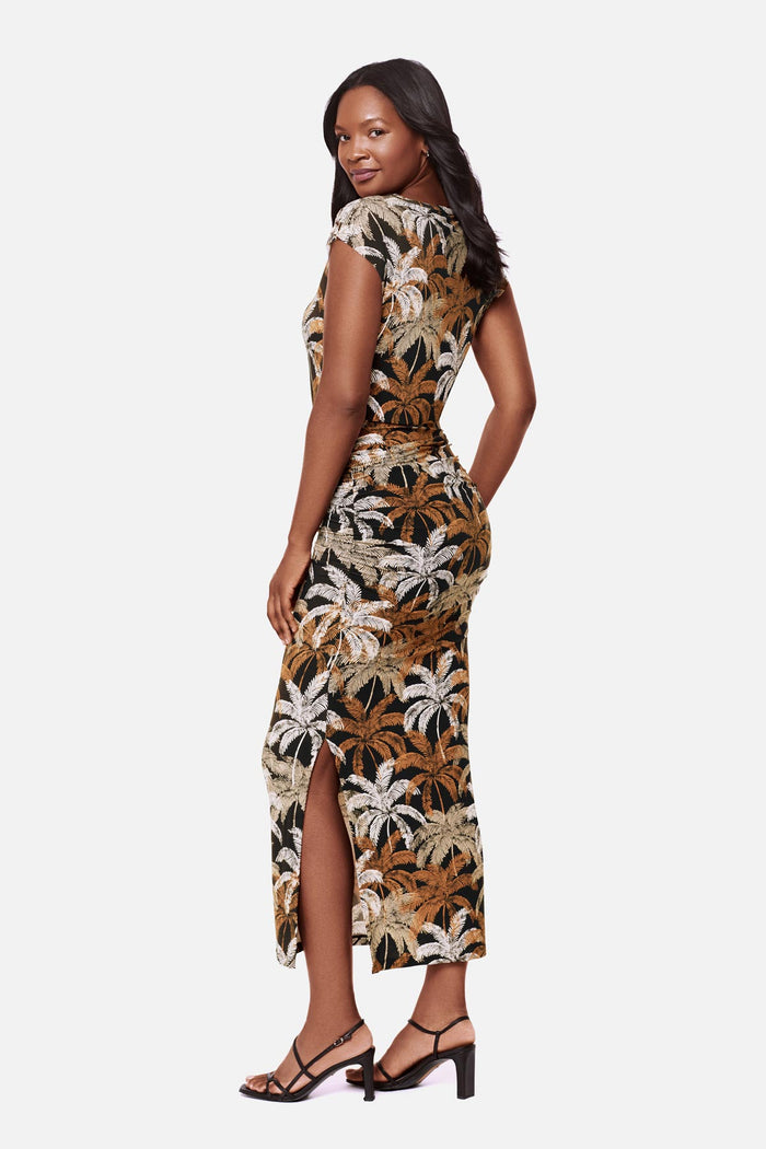 Woman turned left wearing a short sleeve full length dress with a multicolored palm tree print