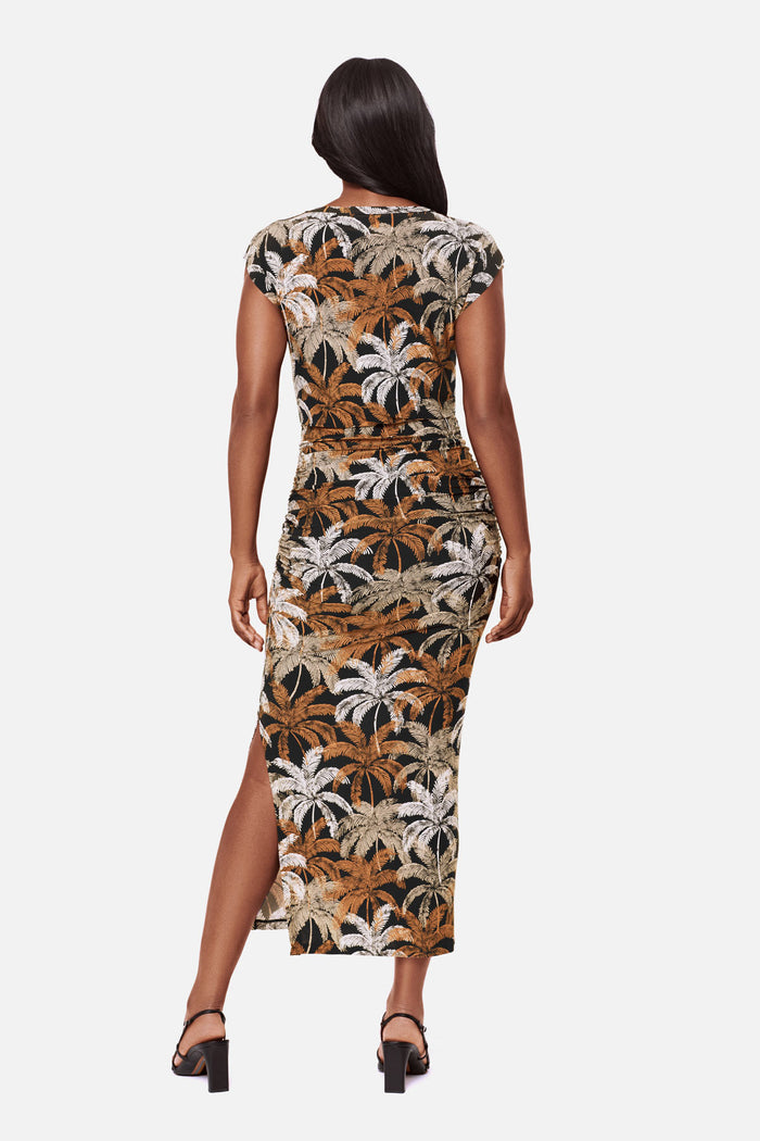 Woman turned away wearing a short sleeve full length dress with a multicolored palm tree print