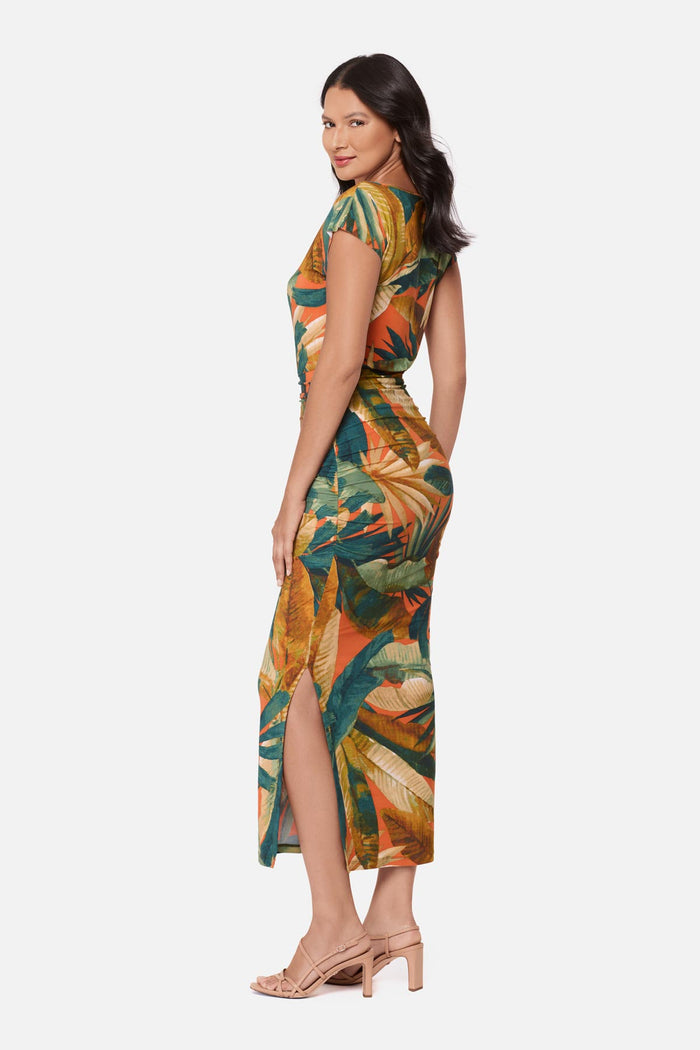 Woman turned left wearing a short sleeve full-length dress with a multicolored tropical print