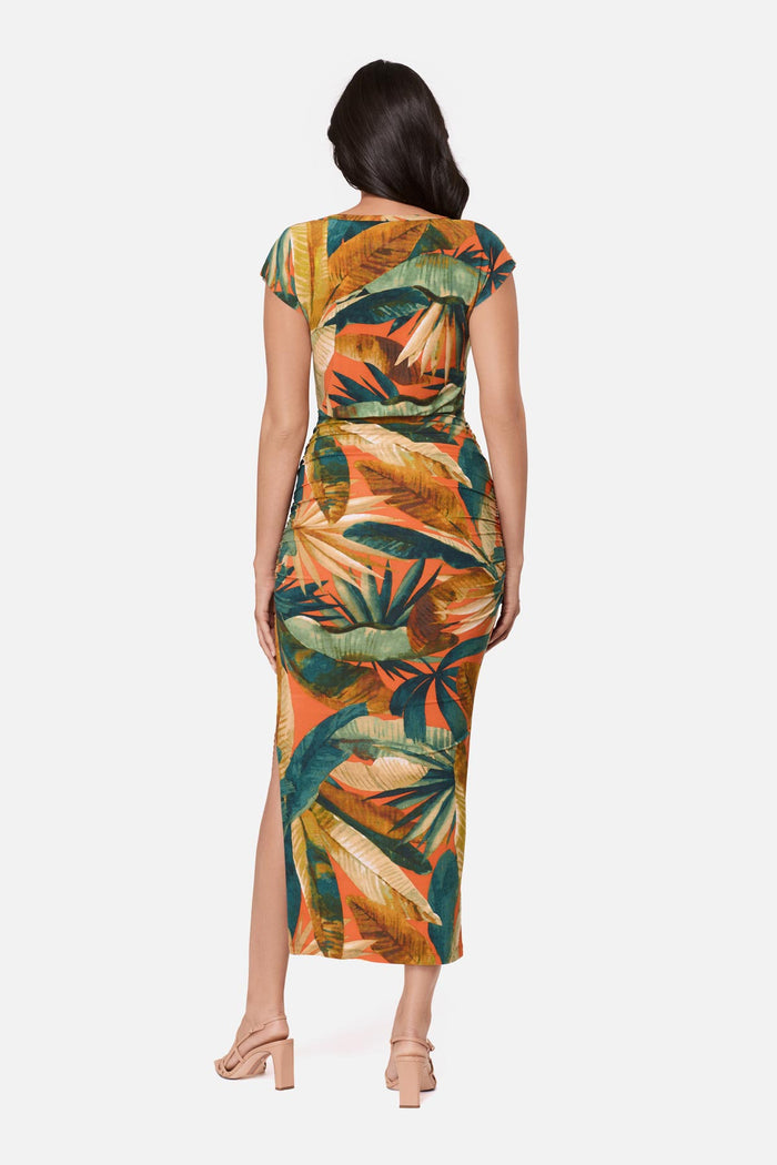 Woman turned away wearing a short sleeve full-length dress with a multicolored tropical print