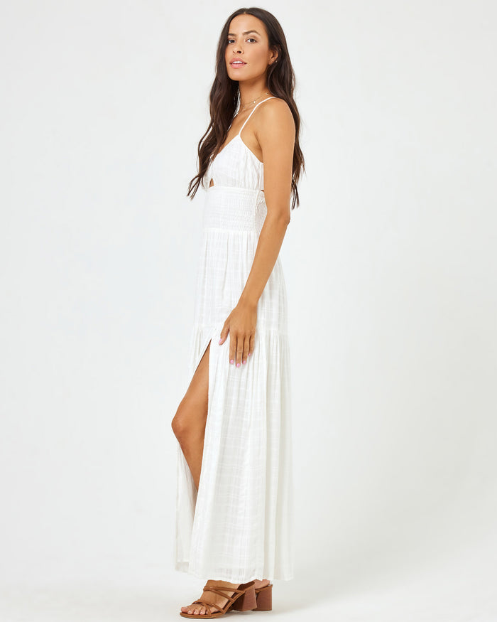 Side view of a model wearing the LSPACE Calla Dress in cream, showing the front slit and tiered skirt.