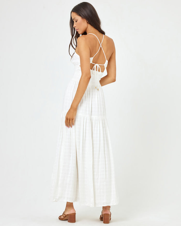 Back angled view of a model wearing the LSPACE Calla Dress in cream, showing the cross-strap back detail with tie closure.