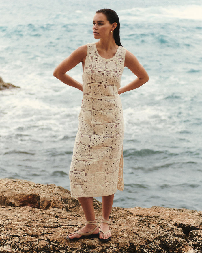 Front view of a model wearing the LSPACE Calla Dress in cream, a sleeveless midi crochet dress with a scoop neckline and square granny-square motif pattern throughout.