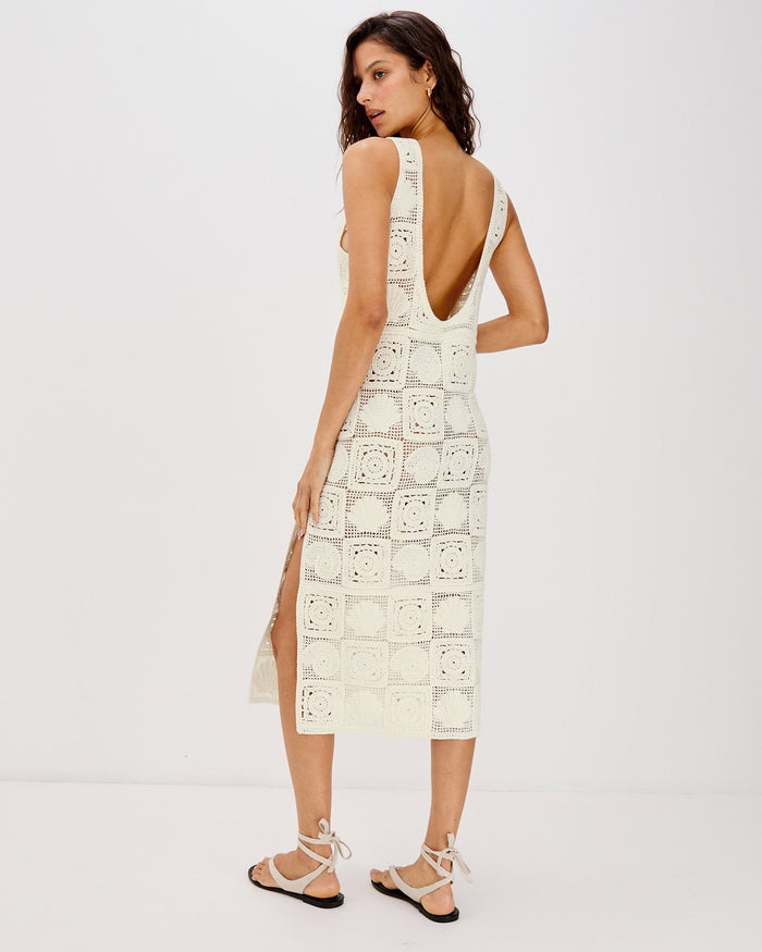 Back view of a model wearing the LSPACE Calla Dress in cream, showing the open-back scoop design and side slit detail on the crochet midi dress.