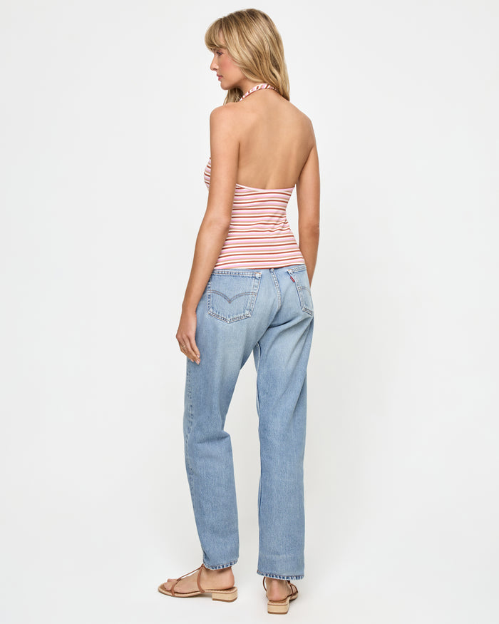 Back view of a model wearing the LSPACE Callie Halter in azalea stripe, showing the open back design and neck-tie closure, styled with light-wash jeans.