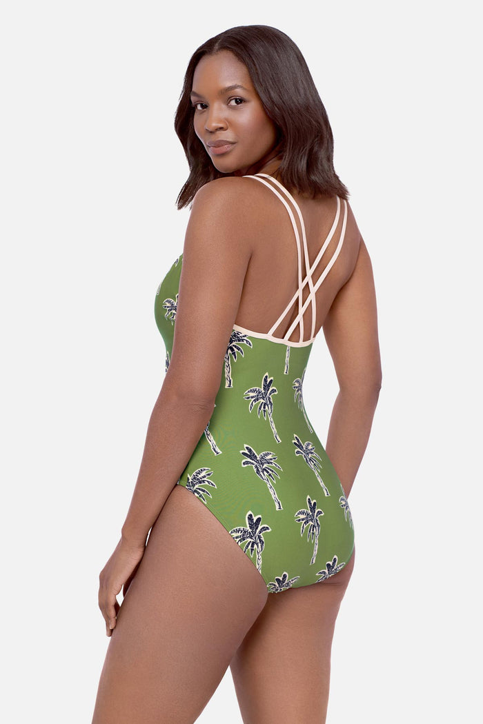 Woman faced left wearing a green palm tree printed one-piece swimsuit