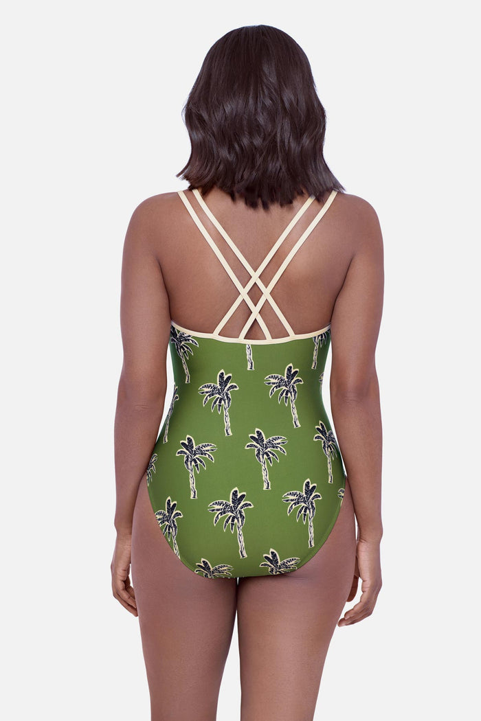 Woman faced away wearing a green palm tree printed one-piece swimsuit