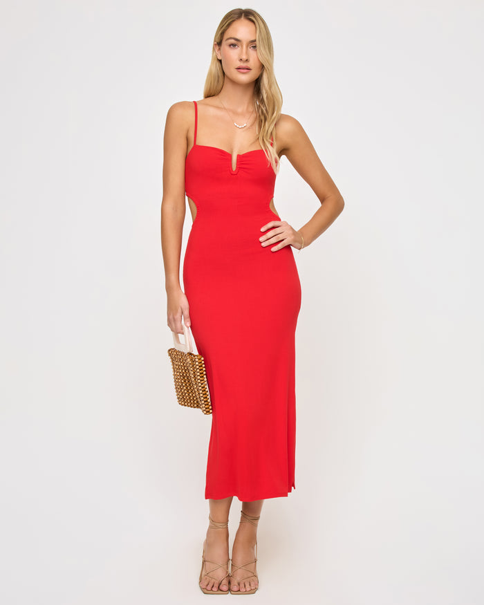Front view of a model wearing the LSPACE Cameron Dress in flame, a red fitted midi dress with thin spaghetti straps, sweetheart neckline with V-notch cutout, and side cutouts at the waist.