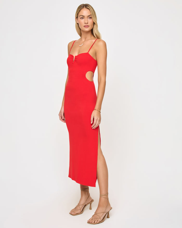 Three-quarter view of a model wearing the LSPACE Cameron Dress in flame, showing the side cutout at the waist and side slit of the red fitted midi dress.