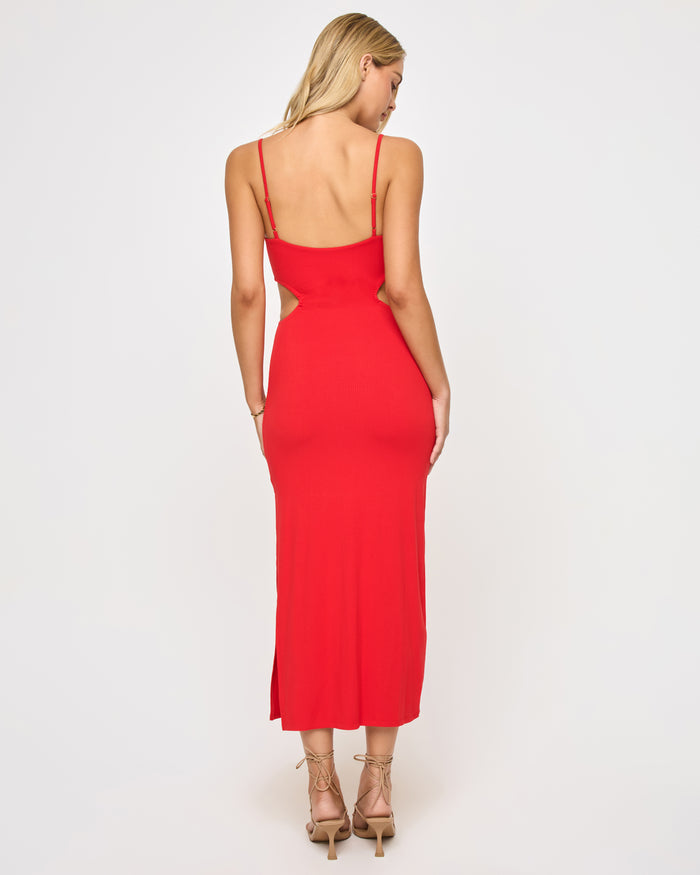 Back view of a model wearing the LSPACE Cameron Dress in flame, showing the open low back, thin spaghetti straps, and side cutouts of the red midi dress.
