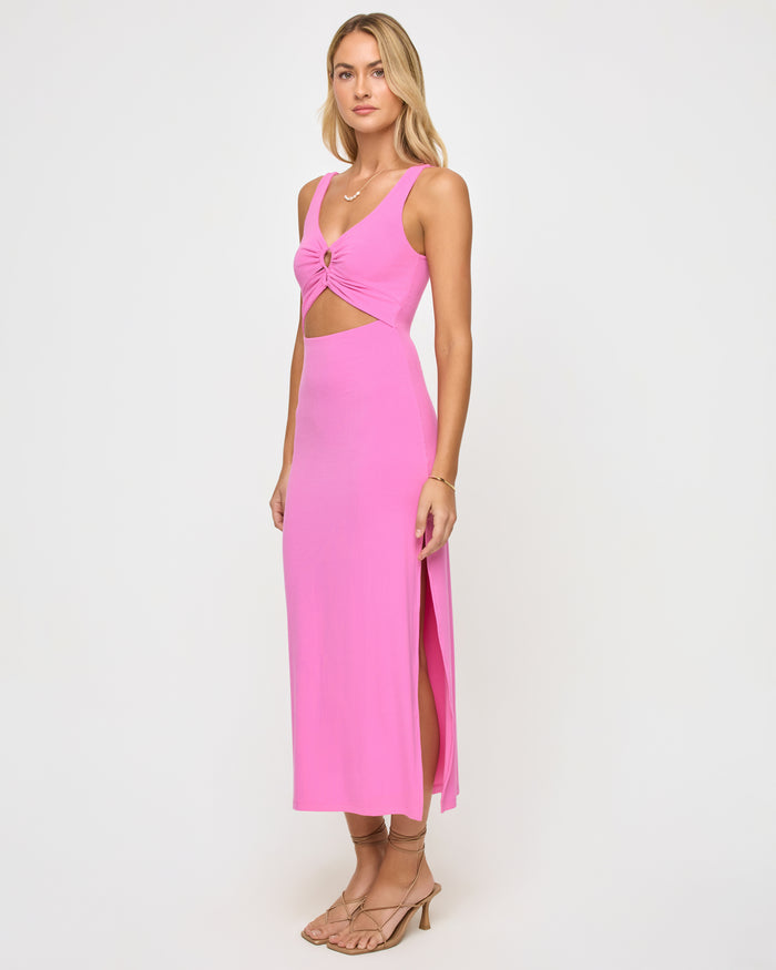 Three-quarter view of a model wearing the LSPACE Camille Dress in hottest pink, showing the side cutout at the waist and side slit of the bright pink fitted midi dress.
