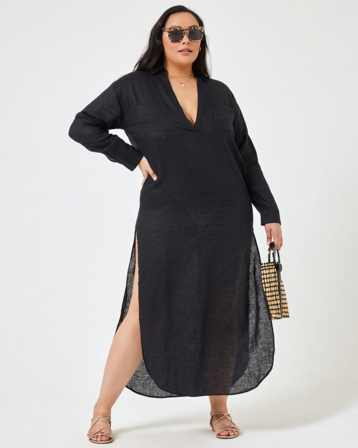 Angled front view of a model wearing the LSPACE Capistrano Tunic in black, a sheer linen maxi with a deep V-neck collar, styled with a woven bag.