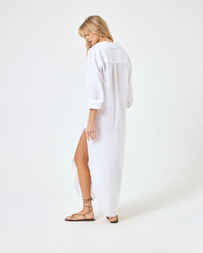 Back angled view of a model wearing the LSPACE Capistrano Tunic in white linen, looking down.