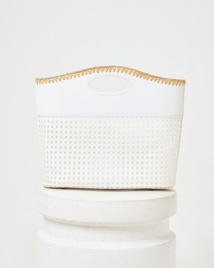 Off-model image of the Casablanca Bag in cream, a structured bag with a rattan weave bottom, cream fabric top, oval cutout handle, and natural trim, on a white pedestal.