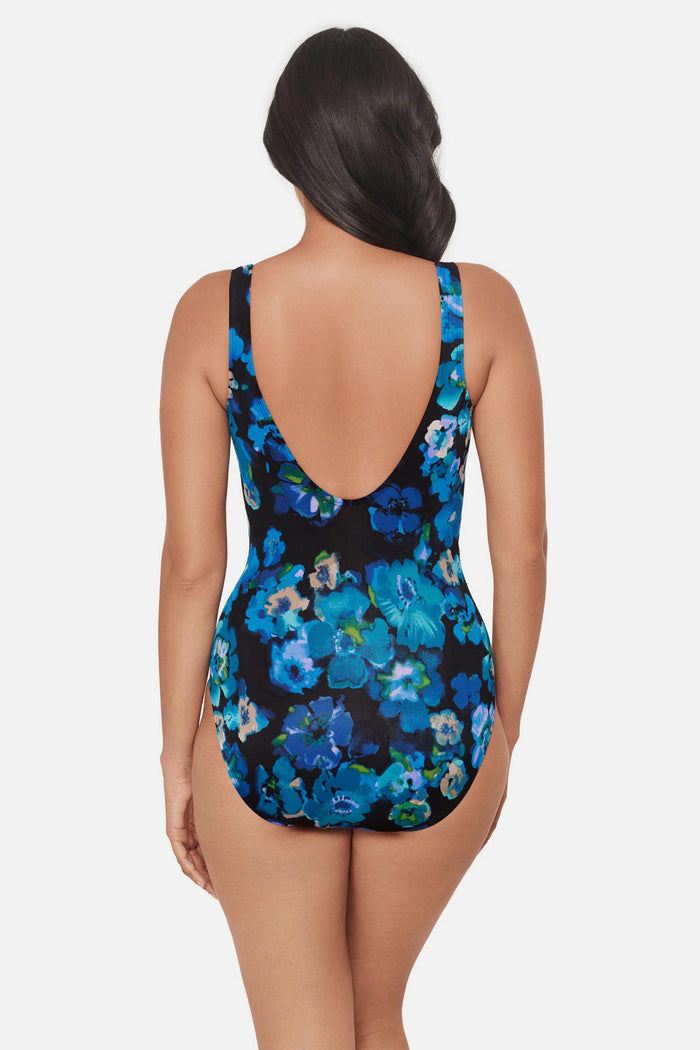 Woman turned away wearing a black and blue floral printed one-piece swimsuit