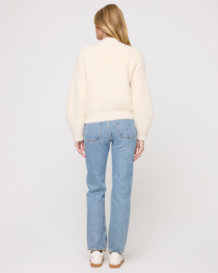 Back view of a model wearing the LSPACE Cosmos Sweater in tapioca, showing the cropped back and fuzzy knit texture.