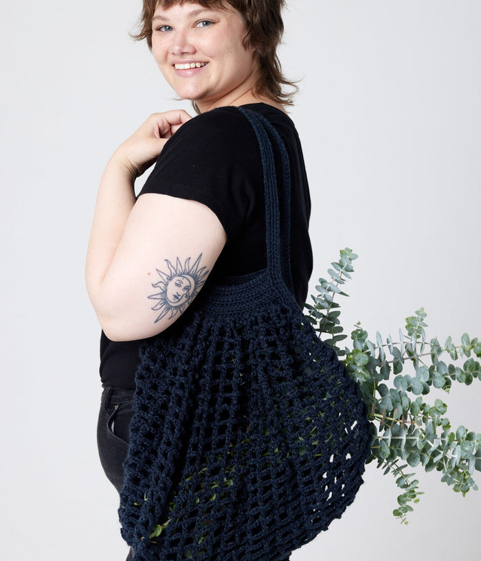 Dark blue bag on model's shoulder with plants inside
