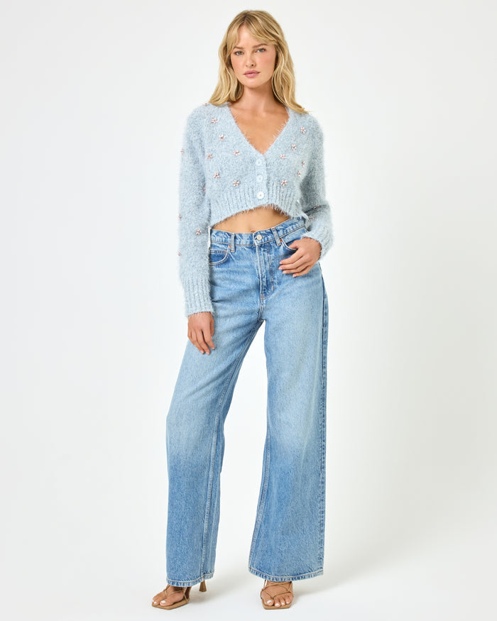Full body front view of a model wearing the LSPACE Crystal Cardigan in dove, a cropped fluffy knit cardigan with scattered crystal floral embellishments, button-front closure, and V-neckline, styled with wide-leg jeans.