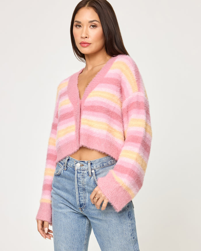 Side view of a model wearing the LSPACE Daybreak Cardigan in daybreak stripe, showing the open-front silhouette and oversized sleeve of the fuzzy striped cardigan.
