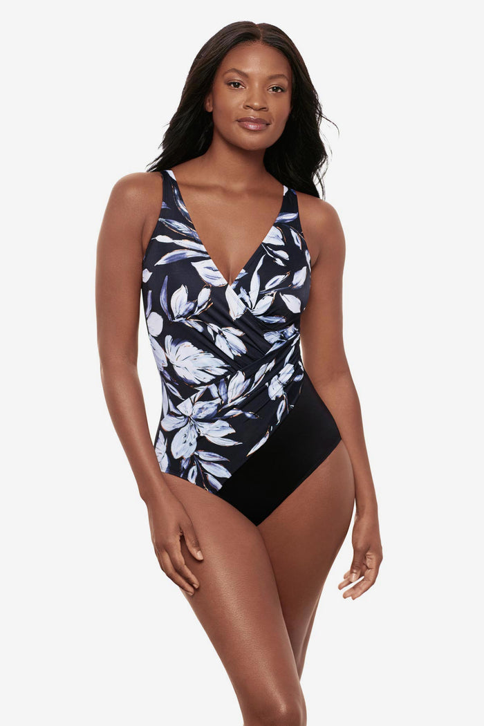 Woman wearing a white floral print one-piece swimsuit with a black panel on the side