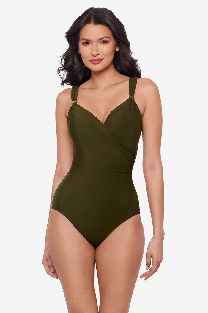 Woman wearing a nori green one-piece swimsuit with details on the straps
