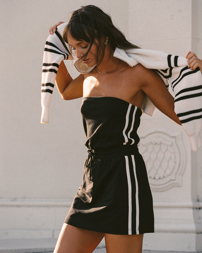 Lifestyle editorial shot of a model wearing the LSPACE Decker Dress in black-cream, in an outdoor setting.