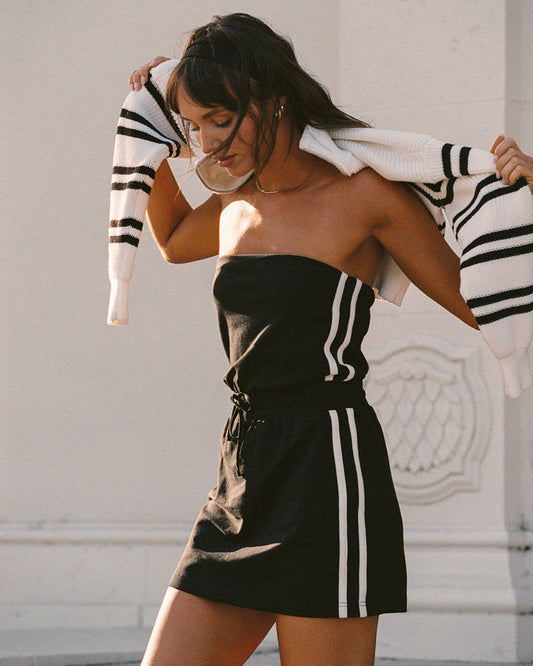 Lifestyle editorial shot of a model wearing the LSPACE Decker Dress in black-cream, in an outdoor setting.