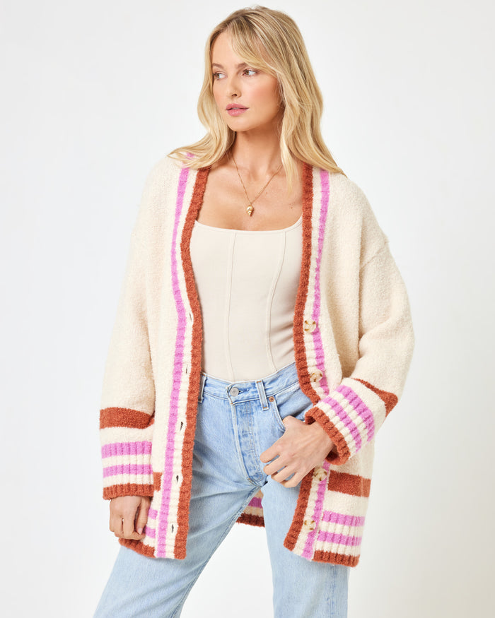 Three-quarter front view of a model wearing the LSPACE Delta Blooms Sweater in delta blooms jacquard, a cozy knit pullover with a floral jacquard pattern in neutral tones, paired with white wide-leg trousers.