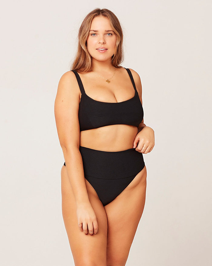 Front view of a model wearing the LSPACE black Desi Bikini Bottom, a ribbed high-waist style, paired with the black Jess Bikini Top.