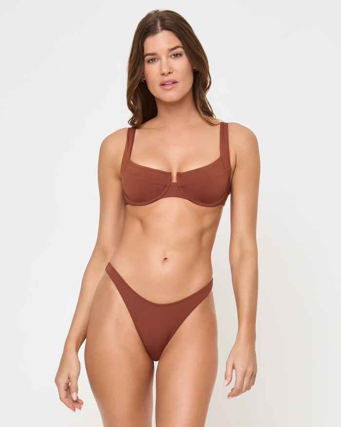 Straight-on front view of a model wearing the tobacco LSPACE Donnie Bikini Bottom with high-cut leg openings in a studio setting, paired with a matching tobacco square-neck underwire Mako Bikini Top with center cut-out.