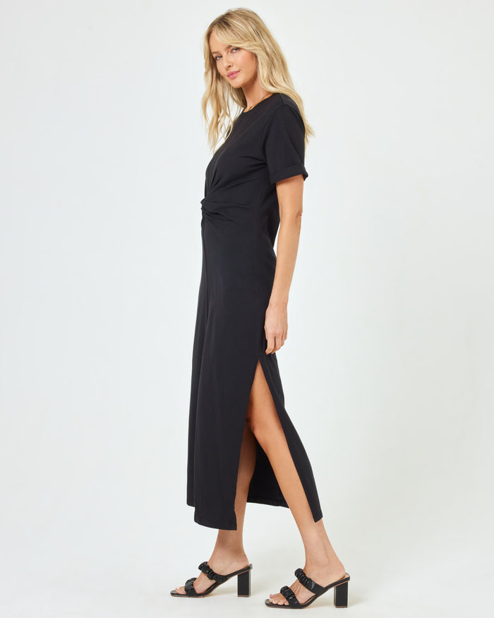 Side view of a model wearing the LSPACE Drew Dress in black, highlighting the twisted waist and side slit.