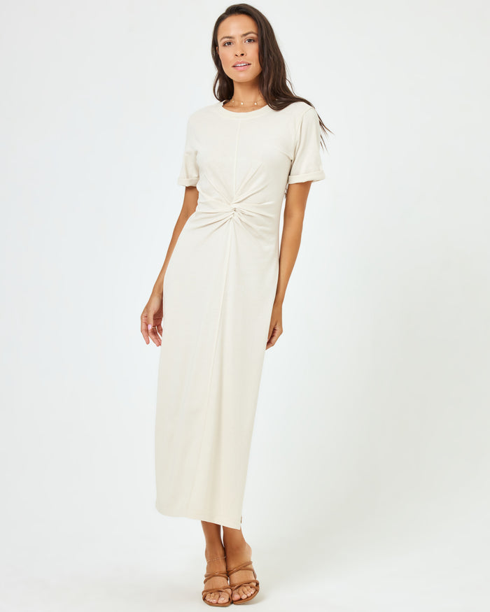 Front view of a model wearing the LSPACE Drew Dress in cream, a short-sleeve jersey midi dress with a ring detail at the twisted waist.