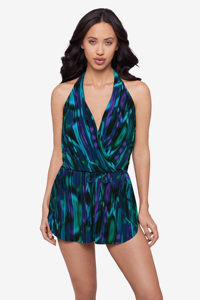 Woman wearing a green and blue pattern swim dress with a deep v neck