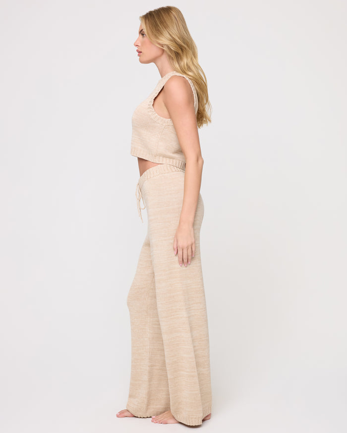Side view of a model wearing the LSPACE En Route Pant - Heather Oatmeal in heather oatmeal, showing the wide-leg silhouette and drawstring waist of the knit pant.