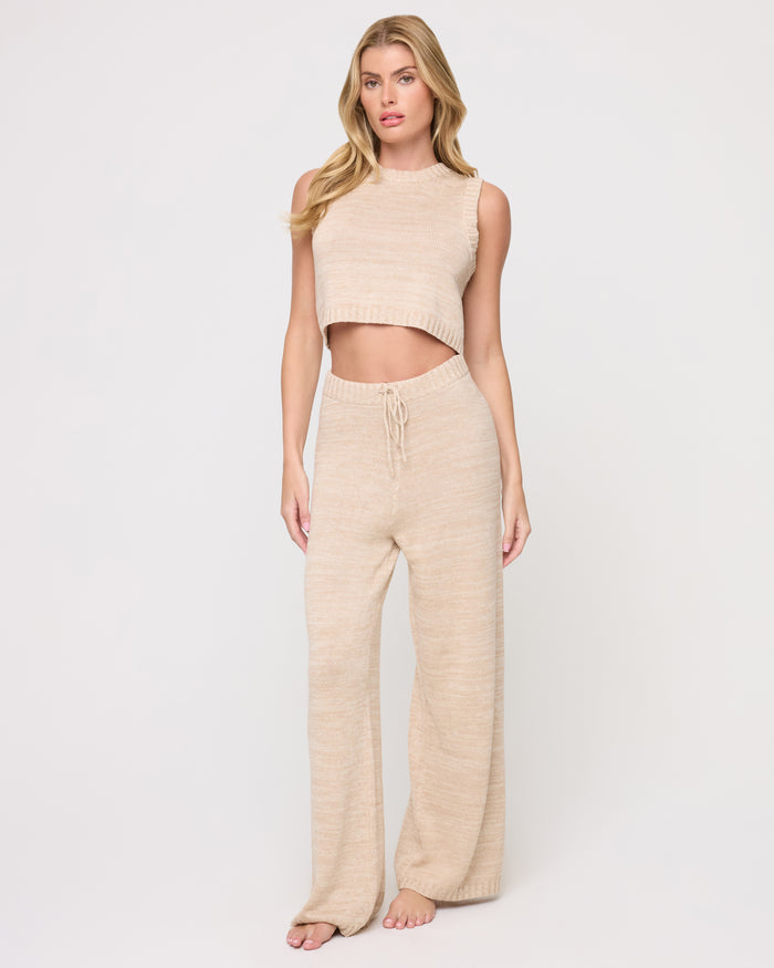 Front view of a model wearing the LSPACE En Route Top - Heather Oatmeal in heather oatmeal, a sleeveless knit crop top with a crew neckline, styled with matching wide-leg knit pants.