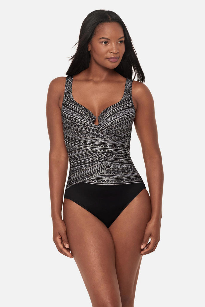 Woman wearing a black and white geometric printed one-piece swimsuit with a sweetheart neckline