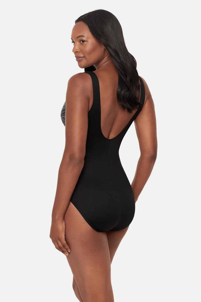 Woman turned left wearing a black and white geometric printed one-piece swimsuit with a sweetheart neckline