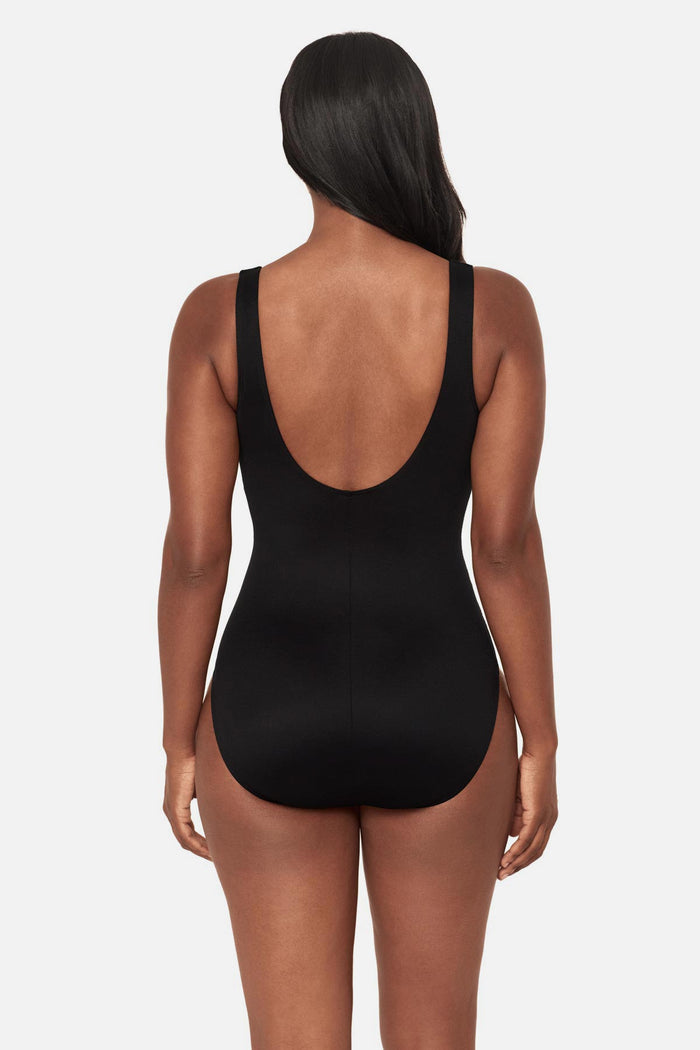 Woman turned away wearing a black and white geometric printed one-piece swimsuit with a sweetheart neckline