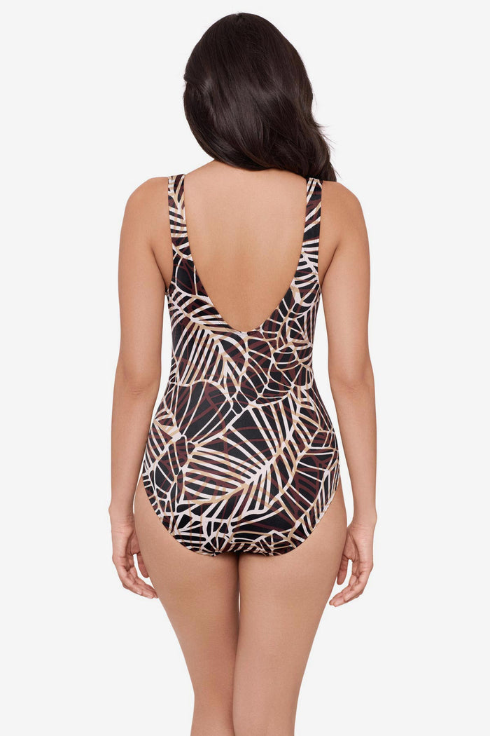 Woman turned away wearing a brown abstract printed one-piece swimsuit