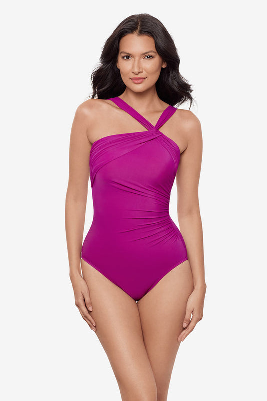 Woman wearing a magenta one-piece swimsuit with an asymmetrical neckline