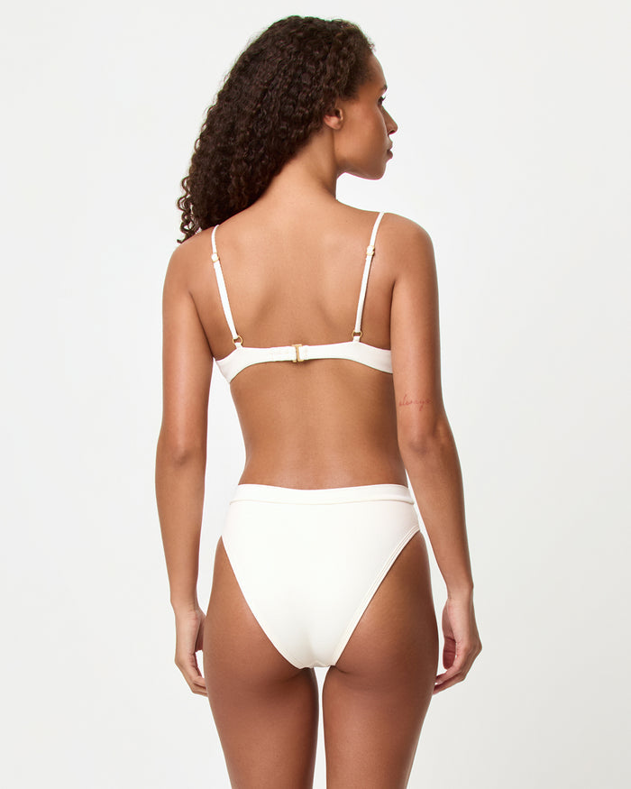 Back view of a model wearing the LSPACE cream Frenchi Bikini Bottom, showing the back coverage and fold-over waistband, paired with the cream Sunrise Shell Bikini Top.