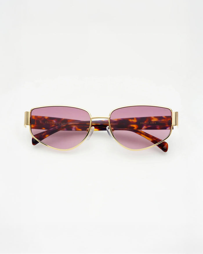 Off-model image of the Freyrs Delilah Sunglasses in gold, folded flat with gold metal frame and pink-tinted lenses.