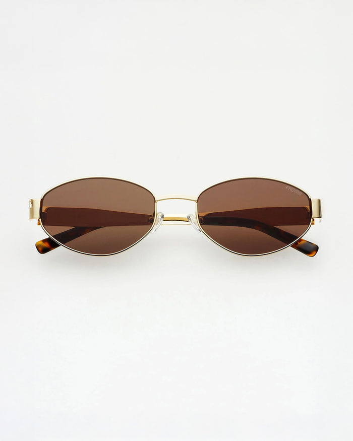 Oval sunglasses with brown tinted lenses, a thin gold metal frame, and tortoiseshell temple tips, shown against a plain white background.