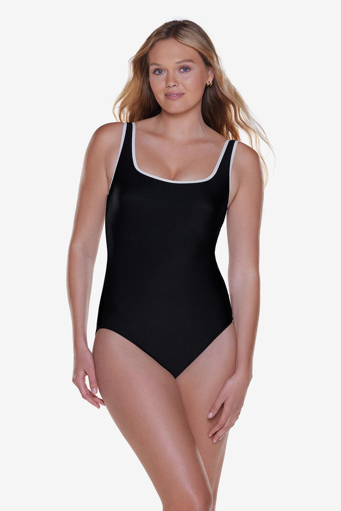 Woman wearing a black one-piece swimsuit with white piping