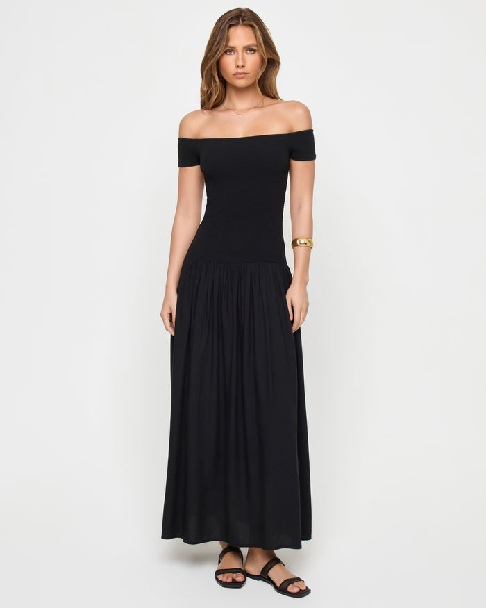 Front view of a model wearing the LSPACE Going Steady Midi in black, a black off-the-shoulder midi dress with fitted ribbed bodice and gathered full skirt.