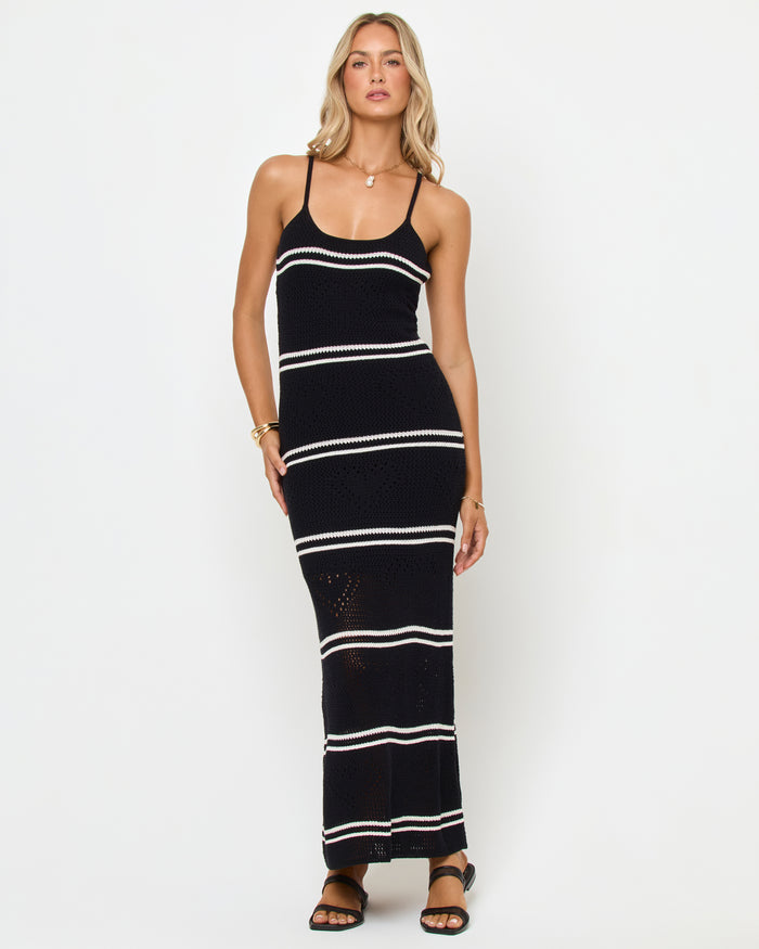 Front view of a model wearing the LSPACE Heart To Heart Dress in black-cream, featuring a body-hugging open-knit crochet maxi silhouette in black with horizontal cream stripe details, scoop neckline, and thin spaghetti straps.