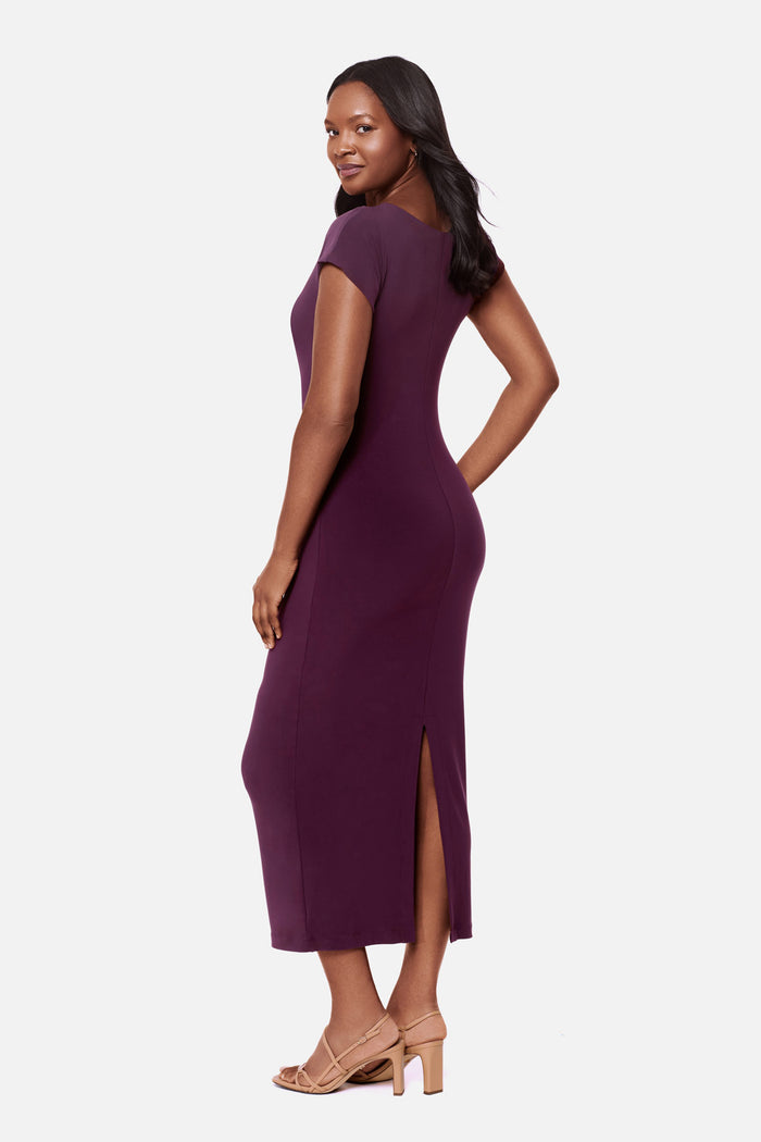 Woman turned left wearing a dark purple short sleeve dress with a gold tone hardware detail on the side